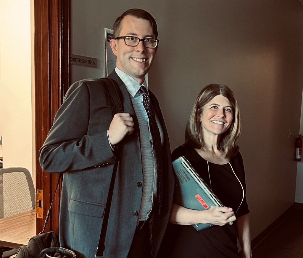 Deb Wilson and her co-counsel Kell Brauer dressed in dark suits and holding a laptop and briefcase on their way to trial.